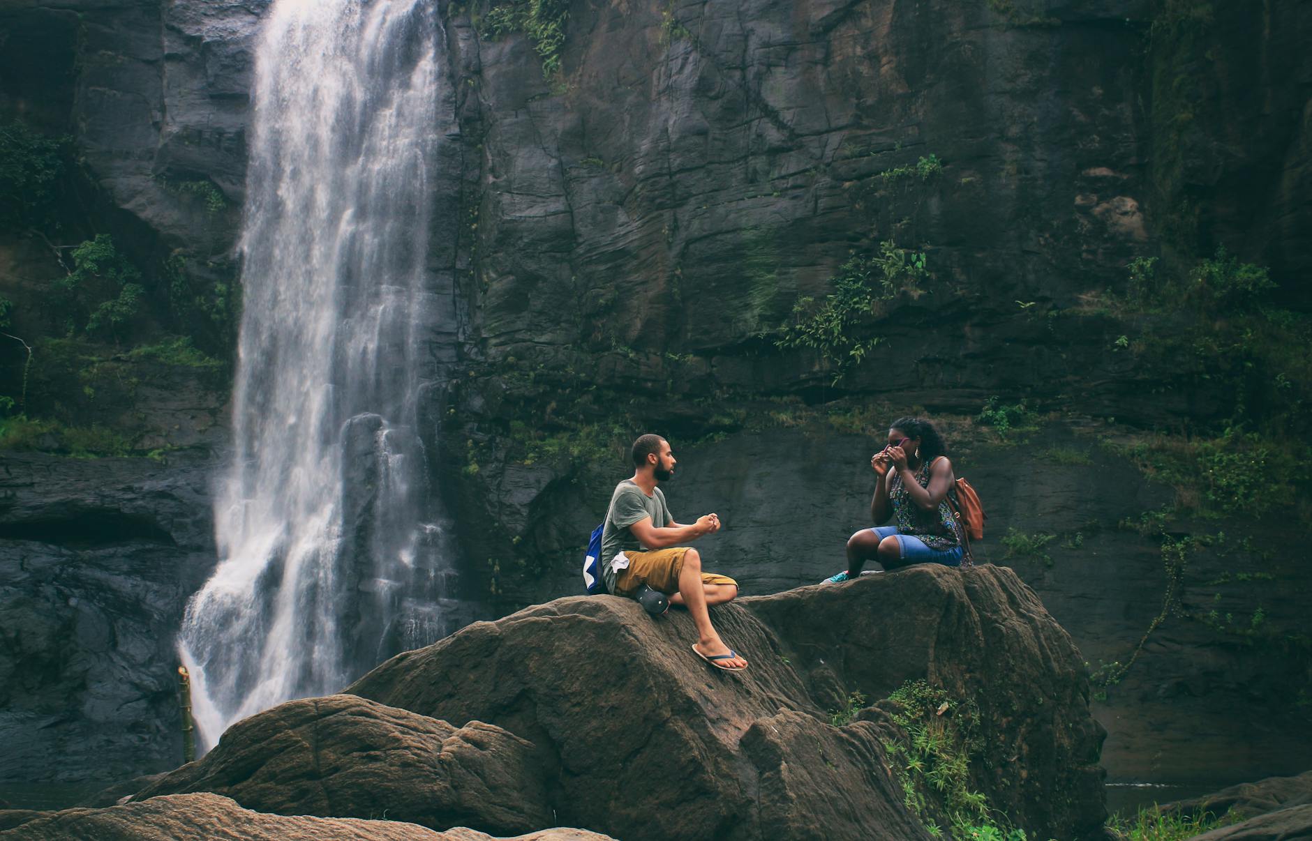 man and woman near waterfall